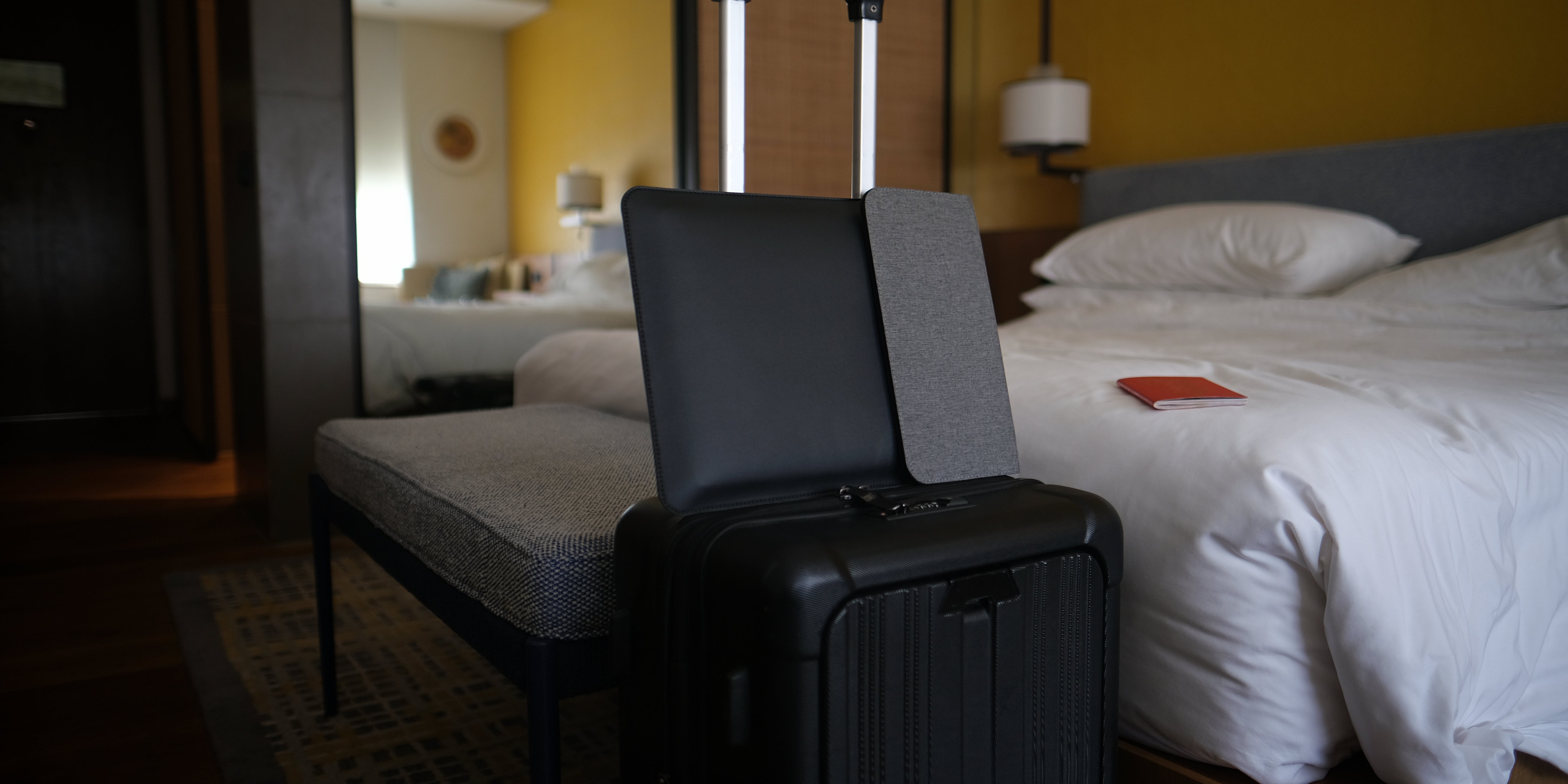 NODE laptop sleeve sat atop a Black suitcase in a hotel room in New Delhi